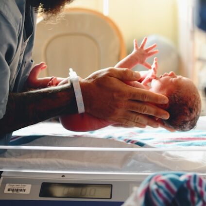 image of a man's hands placing a newborn into a hospital bed